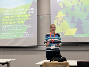 Judith is stood in front of a projector screen with a smile and her arms raised.