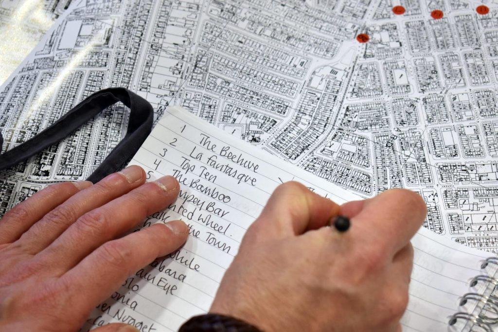 Man writing down names of lost coffee bars on top of a map.