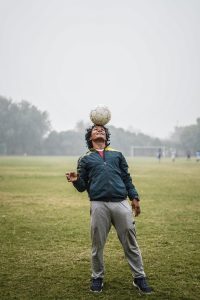 A man heads a ball on a field.