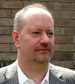 Image of Stephen Wilkinson. A man with a beard wearing a pinstripe blazer.