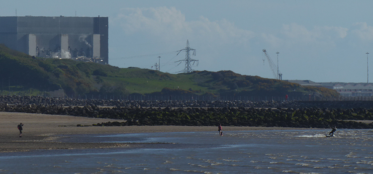 Heysham powerstation next to beach and sea, in which people are doing watersports