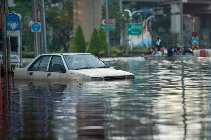 Stock image of a flooded road with a car floating in the water.
