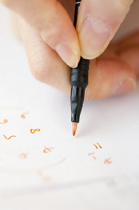 Stock image of a hand holding a pen and writing mathematical equations.