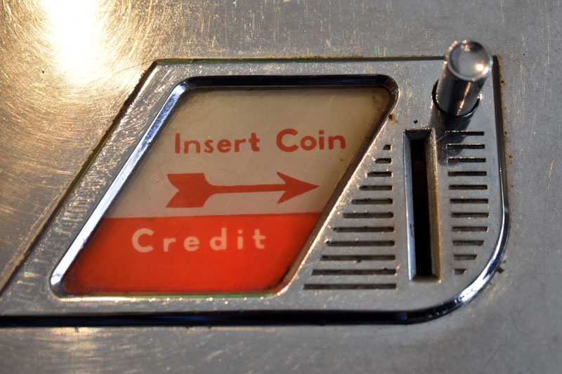 A coin slot on a jukebox. Includes the text 'insert coin' and 'credit'