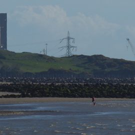 Heysham powerstation next to beach and sea, in which people are doing watersports